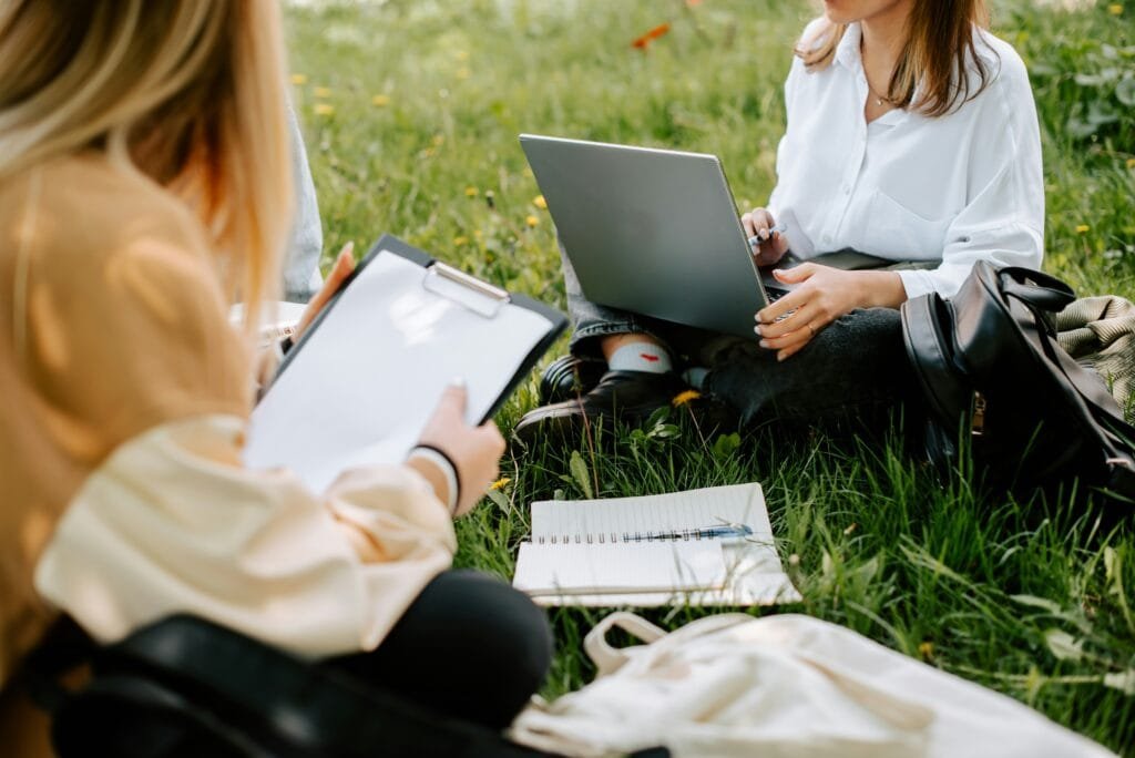 Two Beginners students with laptops studying in the park