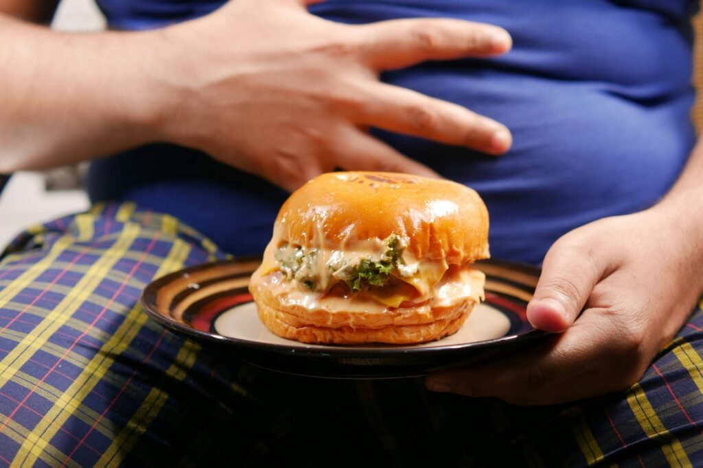 big man trying to eat a burger but he is full showing